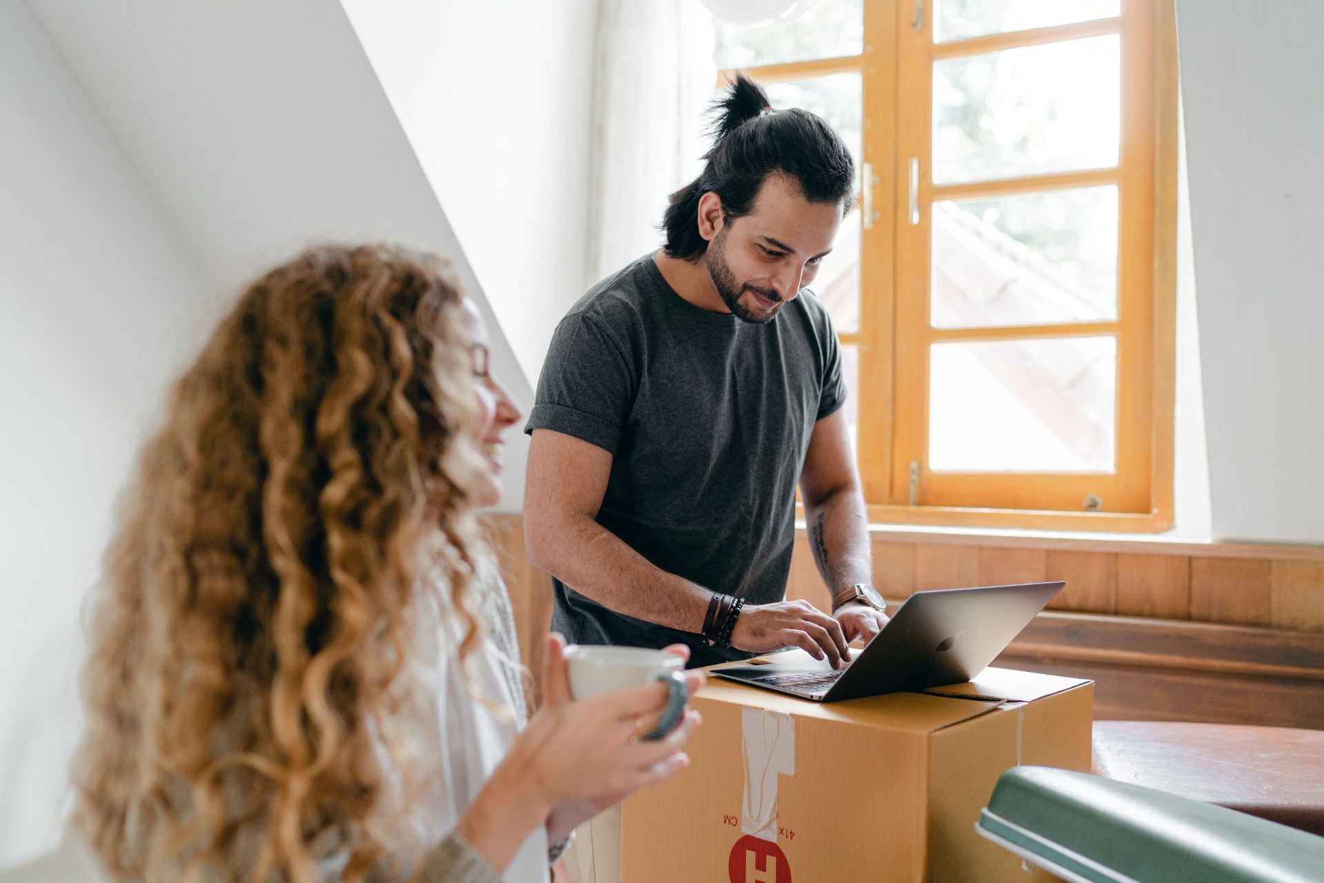 Young couple settling into a new home with a laptop — digital enquiry